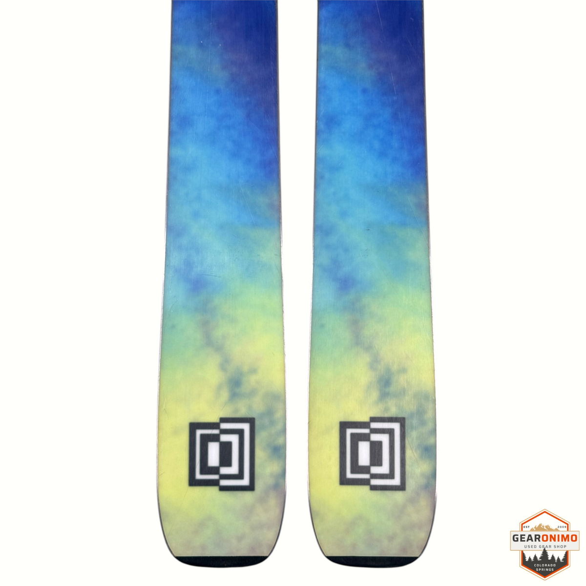 Gearonimo Sports K2 Mindbender 99ti skis featuring a blue and yellow tie-dye pattern with square logo detail