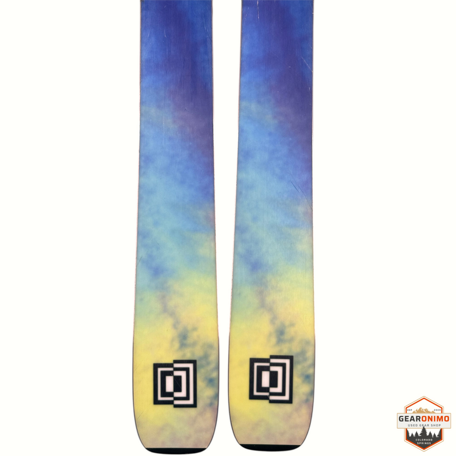 Gearonimo Sports K2 Mindbender 99ti skis featuring a blue and yellow tie-dye pattern and black square logo