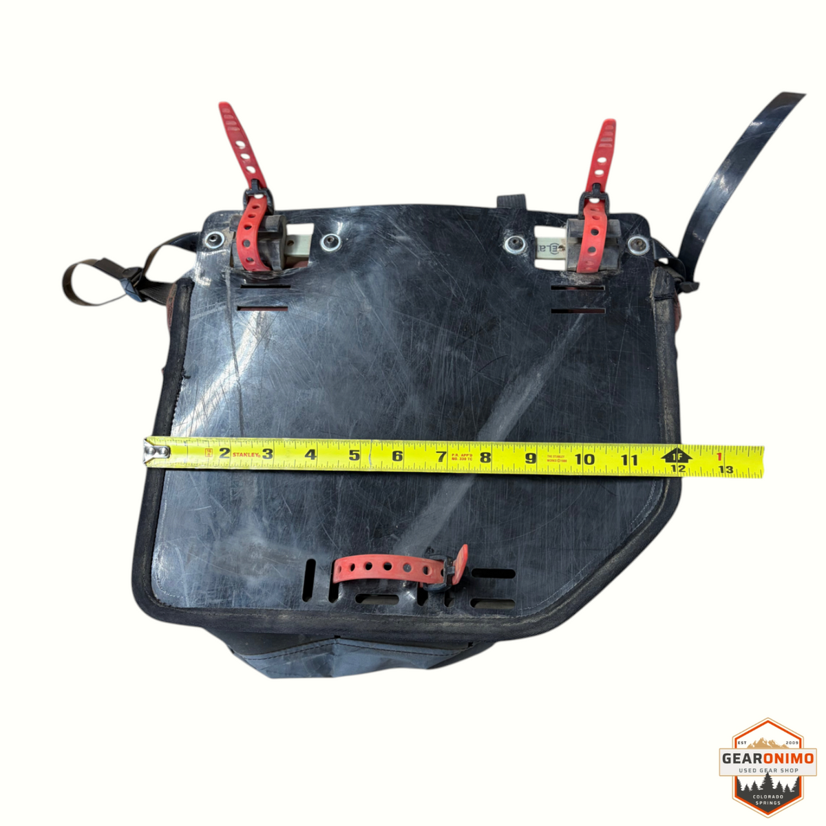 Gearonimo Sports Revelate Designs bicycle pannier with black mounting plate, red straps, and measuring tape.