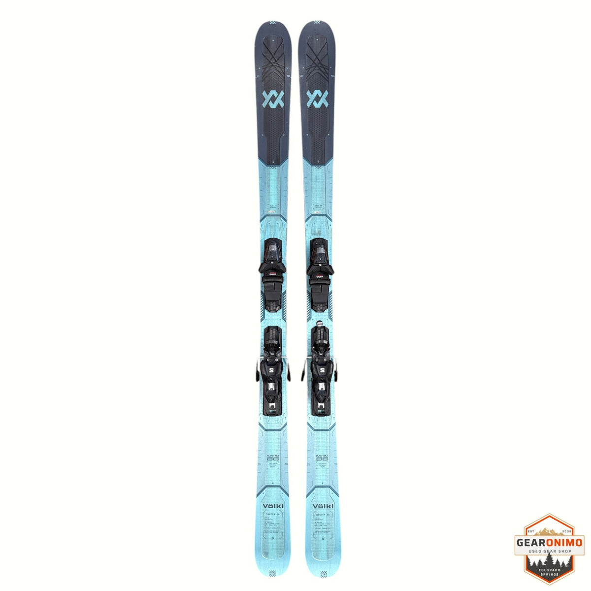 Gearonimo Sports Volkl Mantra 88 skis in blue and grey with mounted bindings, viewed from above on a rustic floor.