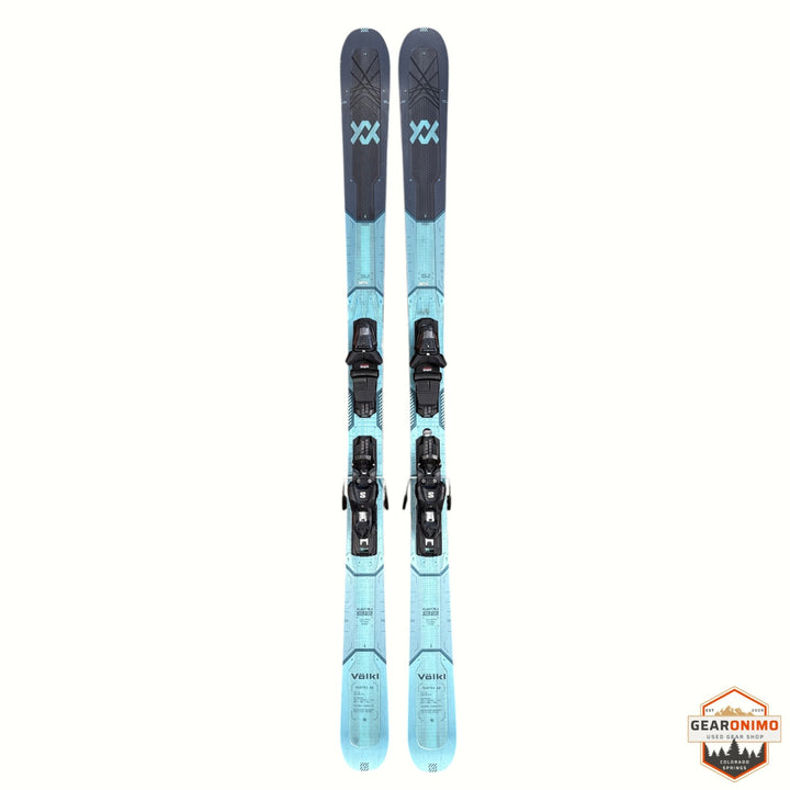 Gearonimo Sports Volkl Mantra 88 skis in blue and grey with mounted bindings, viewed from above on a rustic floor.