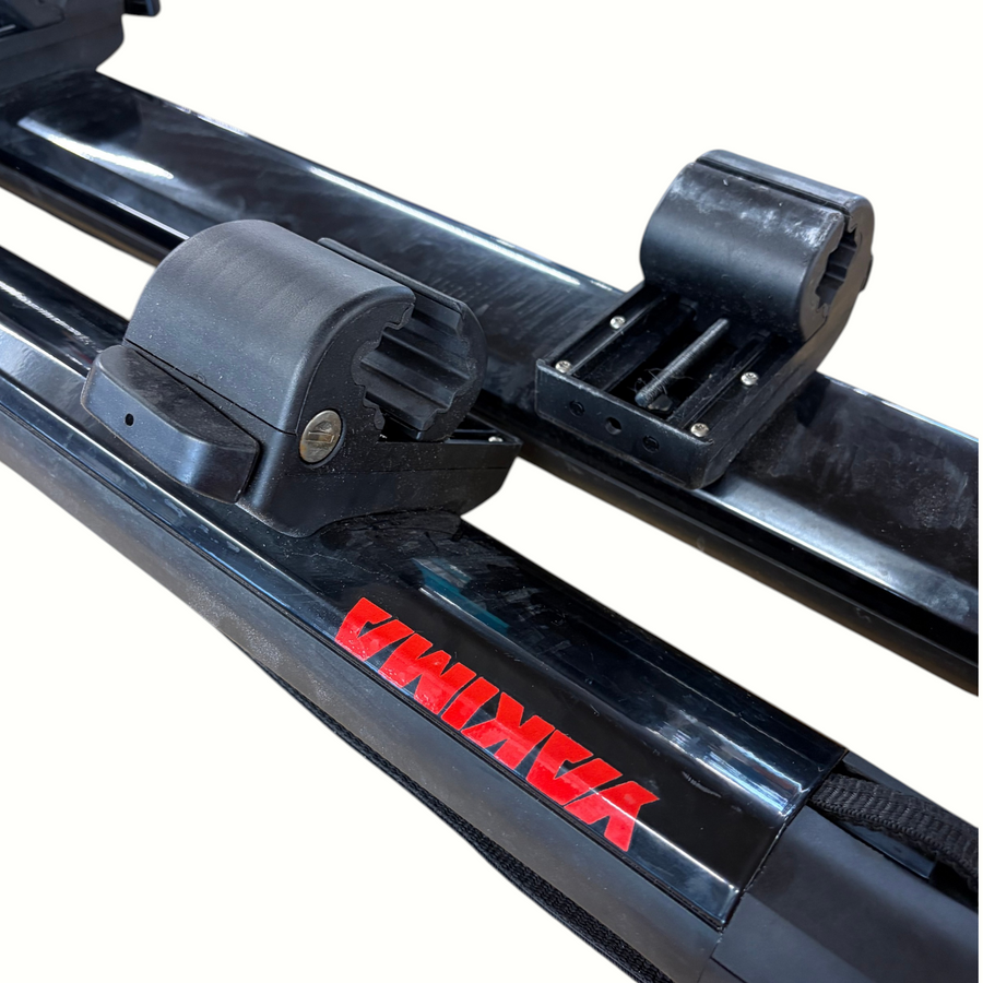 Gearonimo Sports Yakima SUP Dawg roof rack system with black locking mounts and red branding on a cardboard surface